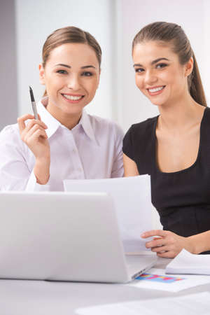 two young business woman or office workers discussing paperwork. picture of two smiling businesswomen working in office and looking at cameraの写真素材
