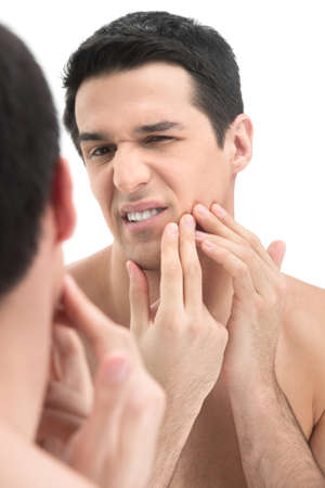 Man in bathroom claening face skin on white background. guy getting rid of pimples on male face in bathroomの写真素材