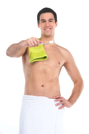 Close up of sexy fit man in towel holding toothbrush. Standing nude isolated over white background looking into cameraの写真素材
