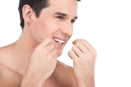 young man flossing his teeth isolated on white background. guy is flossing his teeth in front of bathroom mirrorの写真素材