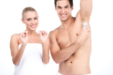 Young handsome man holding deodorant for armpits. beautiful woman standing on white background and holding flossの写真素材