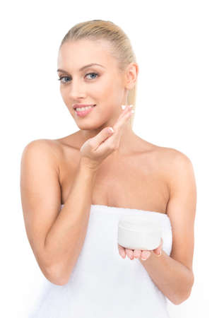 Beautiful women applying moisturizer cosmetic cream on face. Portrait of girl applying cream on white backgroundの写真素材