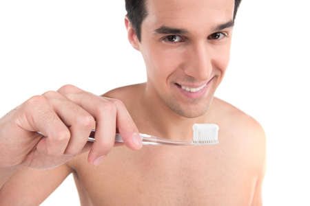 Close up of sexy fit man brushing his teeth. Standing nude isolated over white background looking into cameraの写真素材