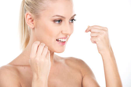 Beautiful young woman using dental floss, isolated on white. Woman flossing teeth, dental careの写真素材