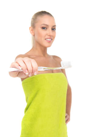 Closeup of toothbrush on foreground with girl smiling on background. pretty blond girl cleaning her teeth with toothbrushの写真素材