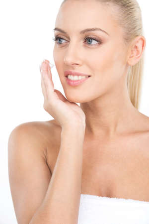 Close up on beautiful women applying moisturizer cosmetic cream on face. Portrait of girl applying cream on white backgroundの写真素材