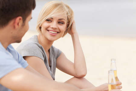 Man and woman relaxing on beach with beer. の写真素材