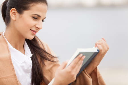 woman reading book covered with blanket. の写真素材