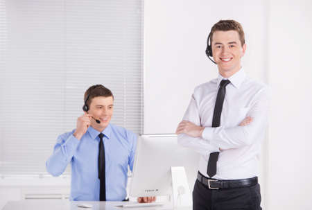 two young call center men talking by phone.の写真素材