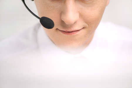 handsome technical support operator working on computer. male mouth with headset portrait at bright call center helpdesk support officeの写真素材