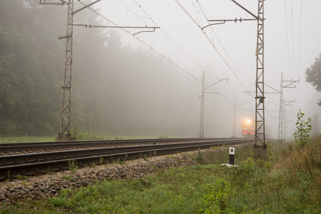 misty country railroad in the early morning with train incomingの写真素材