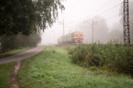 misty country railroad in the early morning with train incomingの写真素材