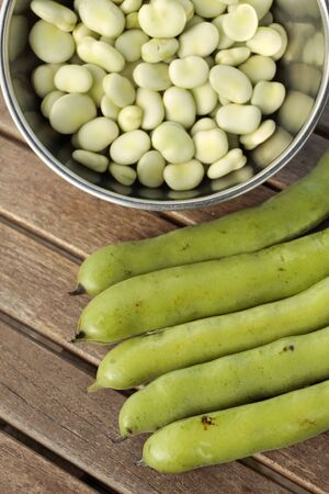 Bowl of broad beans and pods on garden table