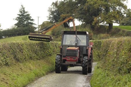 Road hedge cutting vehicle in rural countryside