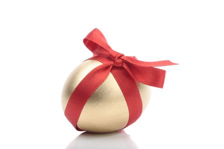 Gold egg with red ribbon over white backgroundの写真素材