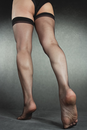 Woman legs wearing black hold-ups over grey backgroundの写真素材
