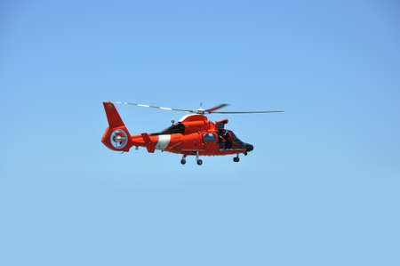 Red rescue helicopter against a bright blue skyの写真素材
