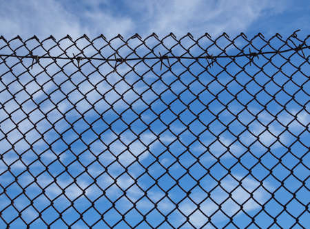 Fence from a mesh chain-link on a background of the sky