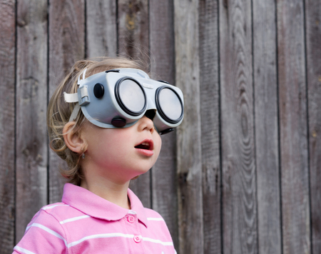 Little blond girl with glasses on wooden backgroundの写真素材