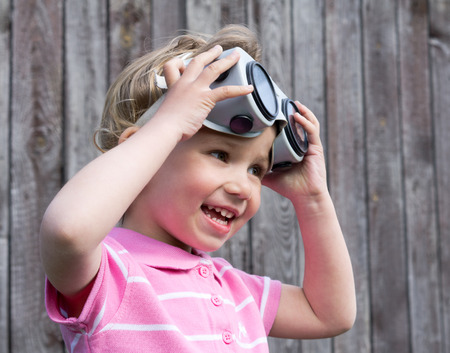 Little blond girl with glasses on wooden backgroundの写真素材