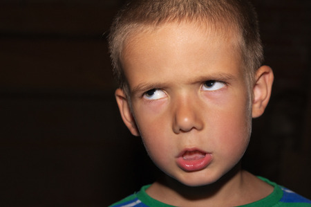 portrait of little angry boy on black backgroundの写真素材