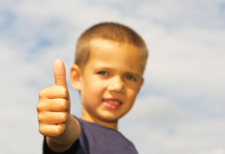 little boy with success finger position and blue sky