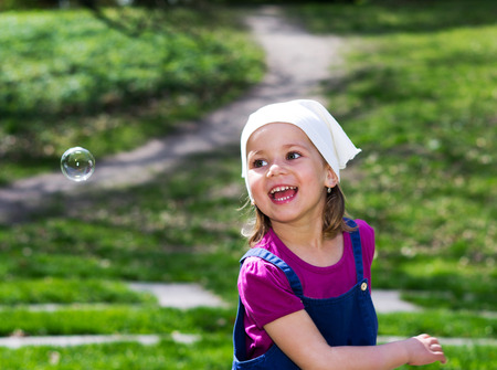 Little girl with bubbles on the summer gardenの写真素材