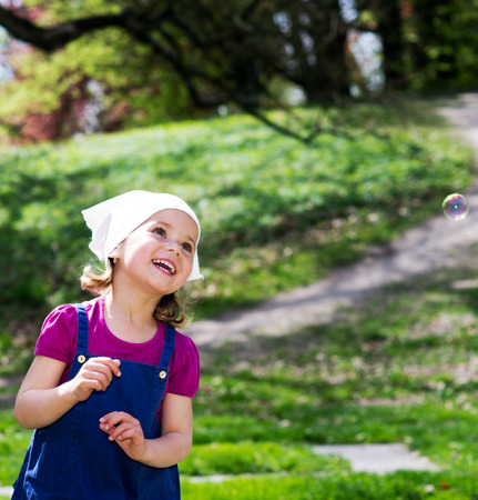 Little girl with bubbles on the summer gardenの写真素材