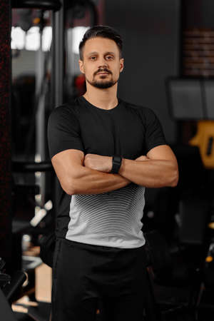 Portrait of personal trainer in sports outfit in fitness center gym standing strong with arms crossedの写真素材