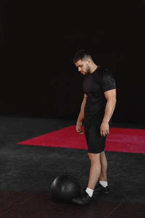Young strong fit muscular man looking at the medicine ball and prepare for crossfit training hard core workout in gym.の写真素材