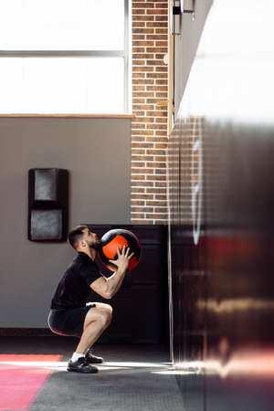 Wall ball training. Young athlete doing wall ball exercise at gym. Crossfit workout conceptの写真素材