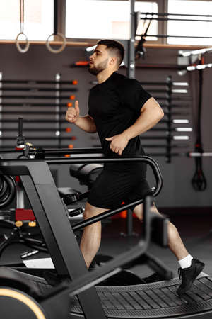 Young man in sportswear running on treadmill at gym.の写真素材