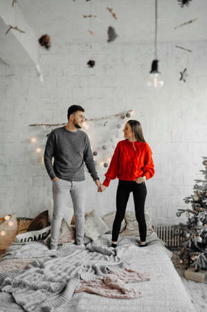 Full length couple of teenagers at Christmas holding hands while standing on a bed enjoying Christmasの写真素材