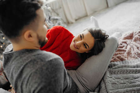 Portrait of a young lady in love looking at her boyfriend lying on his feet spending winter holidays at homeの写真素材