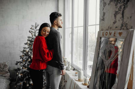 Woman hugging her boyfriend spending winter holidays at home in warm and romantic christmas atmosphere.の写真素材
