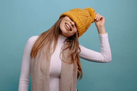 Portrait of funny, positive woman with the hat over his eyes smiling at the camera isolated on a turquoise background. Advertising conceptの写真素材