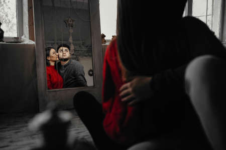 Mirror reflection of a young couple sitting on the floorの写真素材