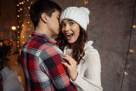 Portrait of two happy people in love wearing winter clothes, having fun together. Excited joyful lovely smiling woman hug her boyfriend and looks at the camera with his mouth openの写真素材