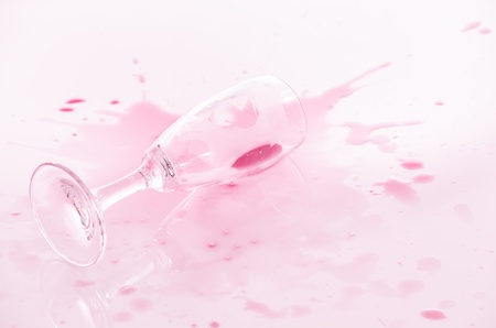 Accidental spillage of red wine across a white surface from a toppled wineglass lying on its side with reflectionの写真素材