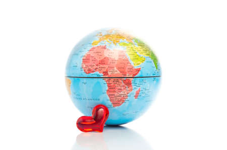 Conceptual image of a colourful globe showing a map of Africa with a small shiny red heart in front of it on a white backgroundの写真素材