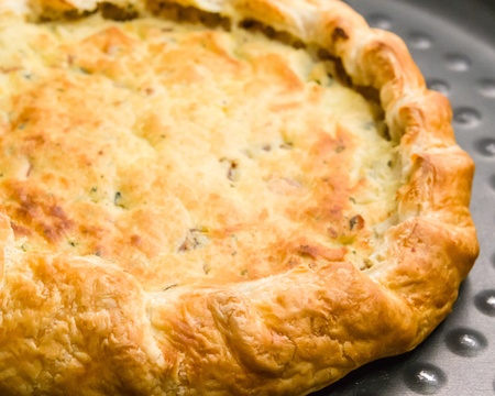 Closeup detail of a delicious freshly baked pie with a decorative crust of light flaky golden pastry