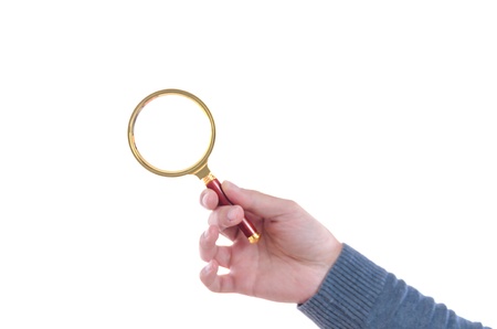 Male hand holding up a circular magnifying glass with a brass metal frame isolated on white