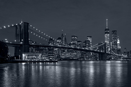 Panoramic view New York City downtown skyline at night and Manhattan Bridge in blue tonalityの写真素材