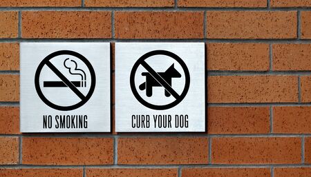 curb your dog and no smoking sign on the wallの写真素材