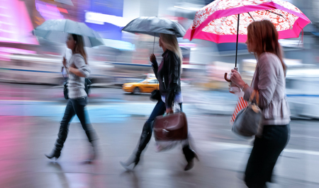 business people walking in the street on a rainy day motion blurredの写真素材