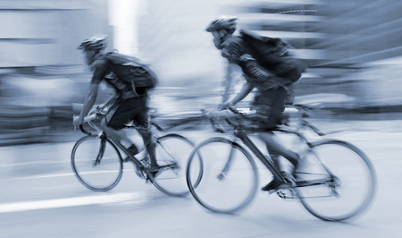 cyclist in traffic on the city roadway  motion blur and blue tonality