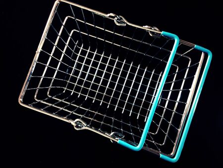 View of metallic shopping basket isolated in black background.の素材