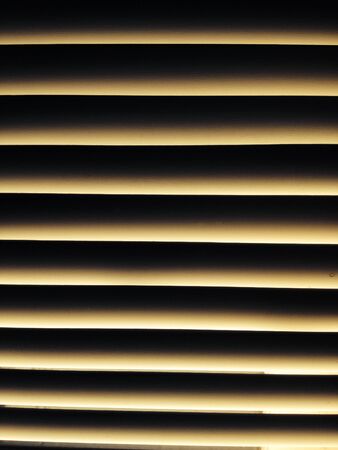 View of closed window blind with light shadow patternの素材