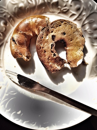Half of toasted and eaten bagel and spread with knifeの素材