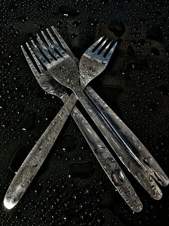 Little stack of forks isolated in black backgroundの素材